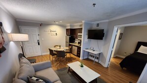 A modern living room with a sofa, a coffee table, and a dining area. - First Floor Family Disney Universal Orlando (Kissimmee)