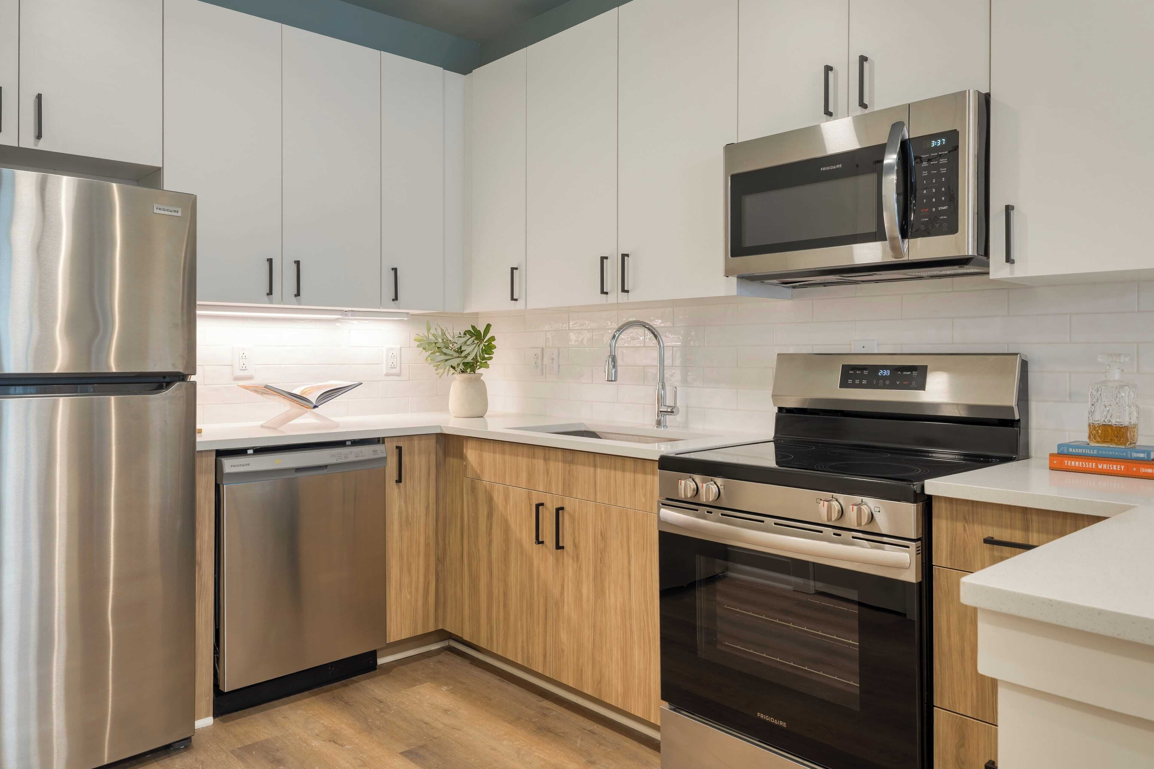 Una cocina moderna con electrodomésticos de acero inoxidable, armarios blancos y encimera de madera.