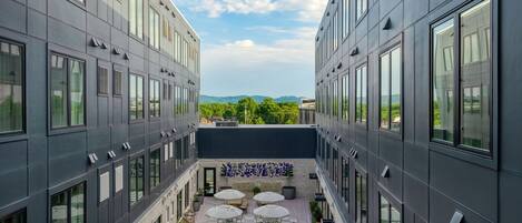 A modern building with a courtyard featuring outdoor seating and potted plants.