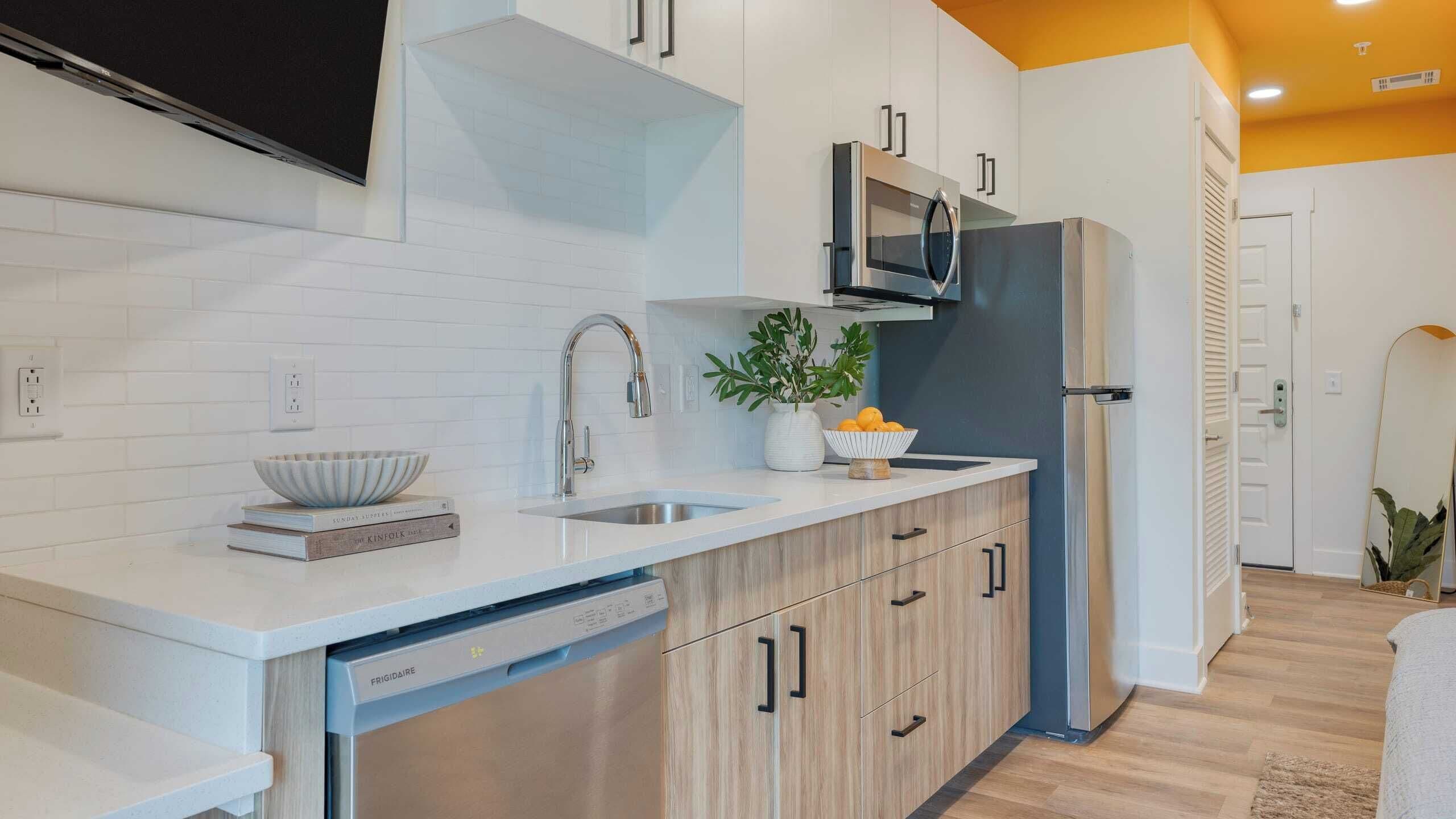A modern kitchen with white cabinetry, a built-in dishwasher, a microwave, and a refrigerator.