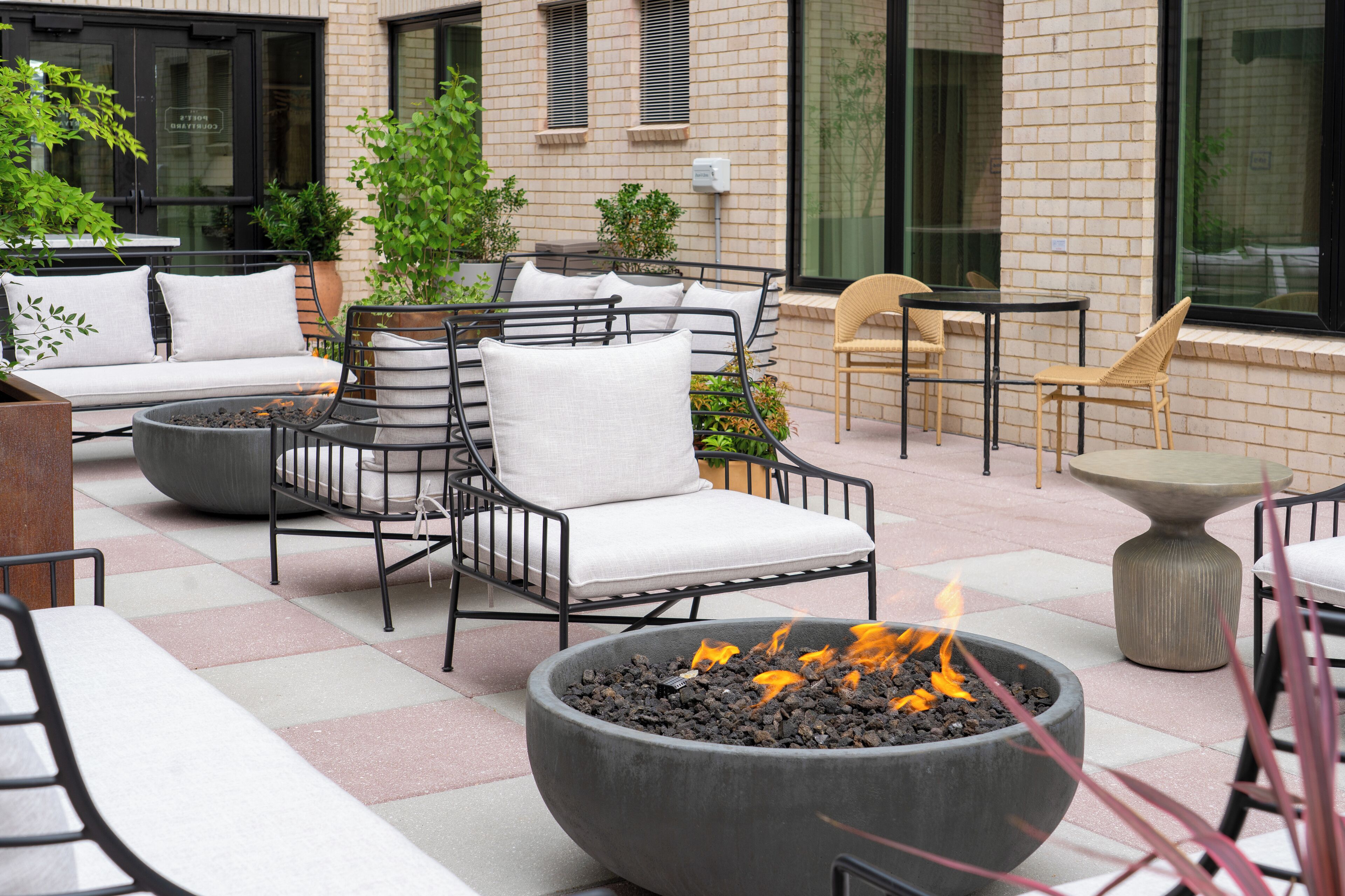 An outdoor seating area with a fire pit, cushioned chairs, and tables.