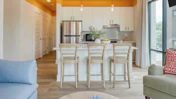 Una cocina moderna con una isla central, taburetes de bar y un comedor con un tablero de ajedrez.