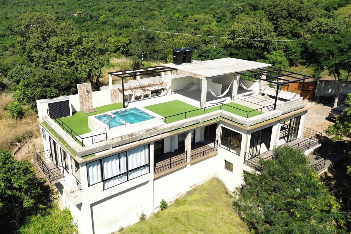 A modern house with a rooftop pool, large windows, and a spacious deck.