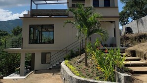 A modern two-story building with a flat roof, large windows, and a staircase leading to the upper level. - Alto Casa de Montaña (Santa Marta)
