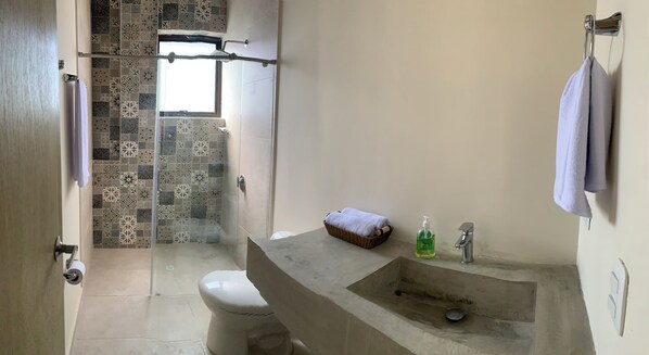 A bathroom with a shower, toilet, and sink.