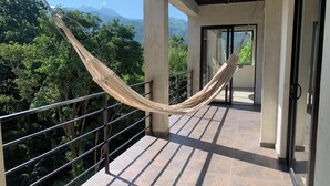 A hammock on a balcony with a view of lush greenery and mountains. - Alto Casa de Montaña (Santa Marta)