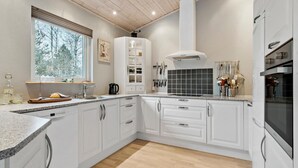 A modern kitchen with white cabinetry, a large window, and a view of trees outside. - Amazing home in Højslev with sauna (Højslev)