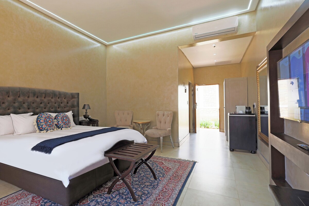 A hotel room with a large bed, a desk, a chair, and a TV.