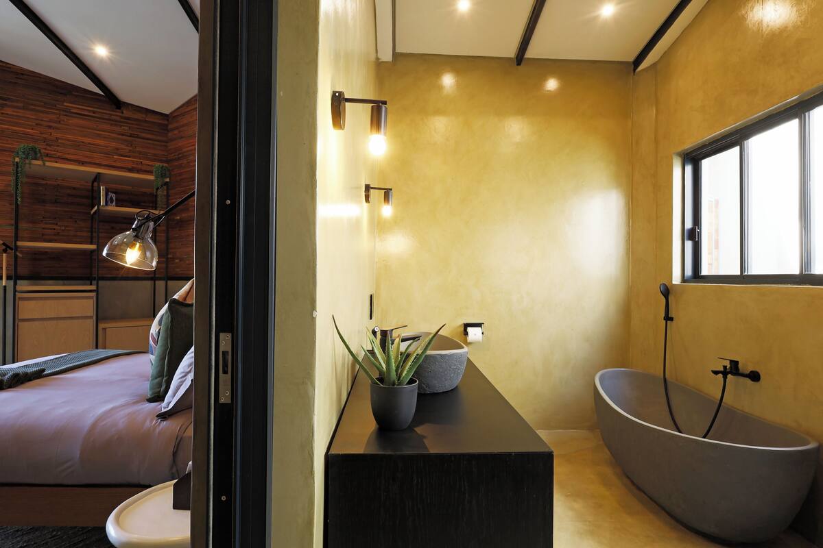 Un bagno moderno con una vasca da bagno indipendente, uno specchio grande e una pianta in vaso.