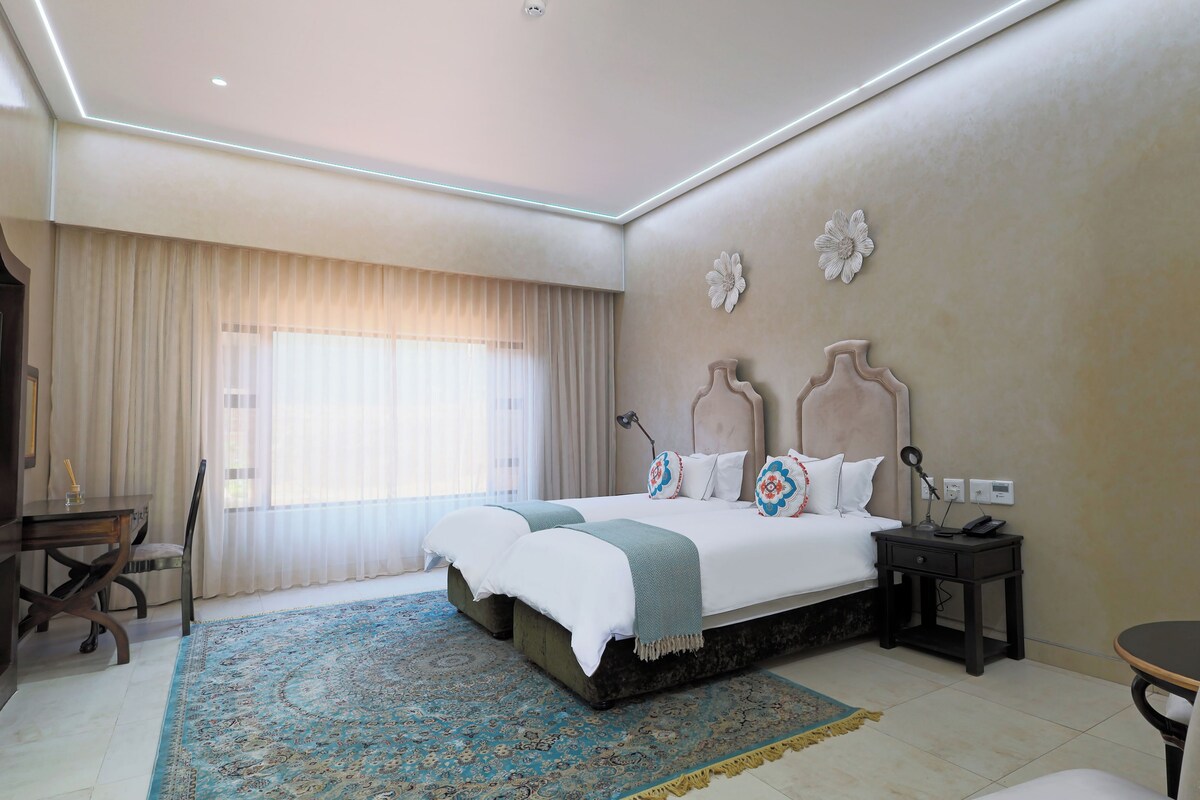 A hotel room with a large bed, a desk, a chair, and a small table.