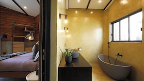 A modern bathroom with a freestanding bathtub, a large mirror, and a potted plant.