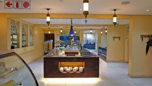 A hotel lobby with a central reception desk, decorative wall patterns, and a tiled floor. - Qurtuba Resort And Events (Johannesburg)