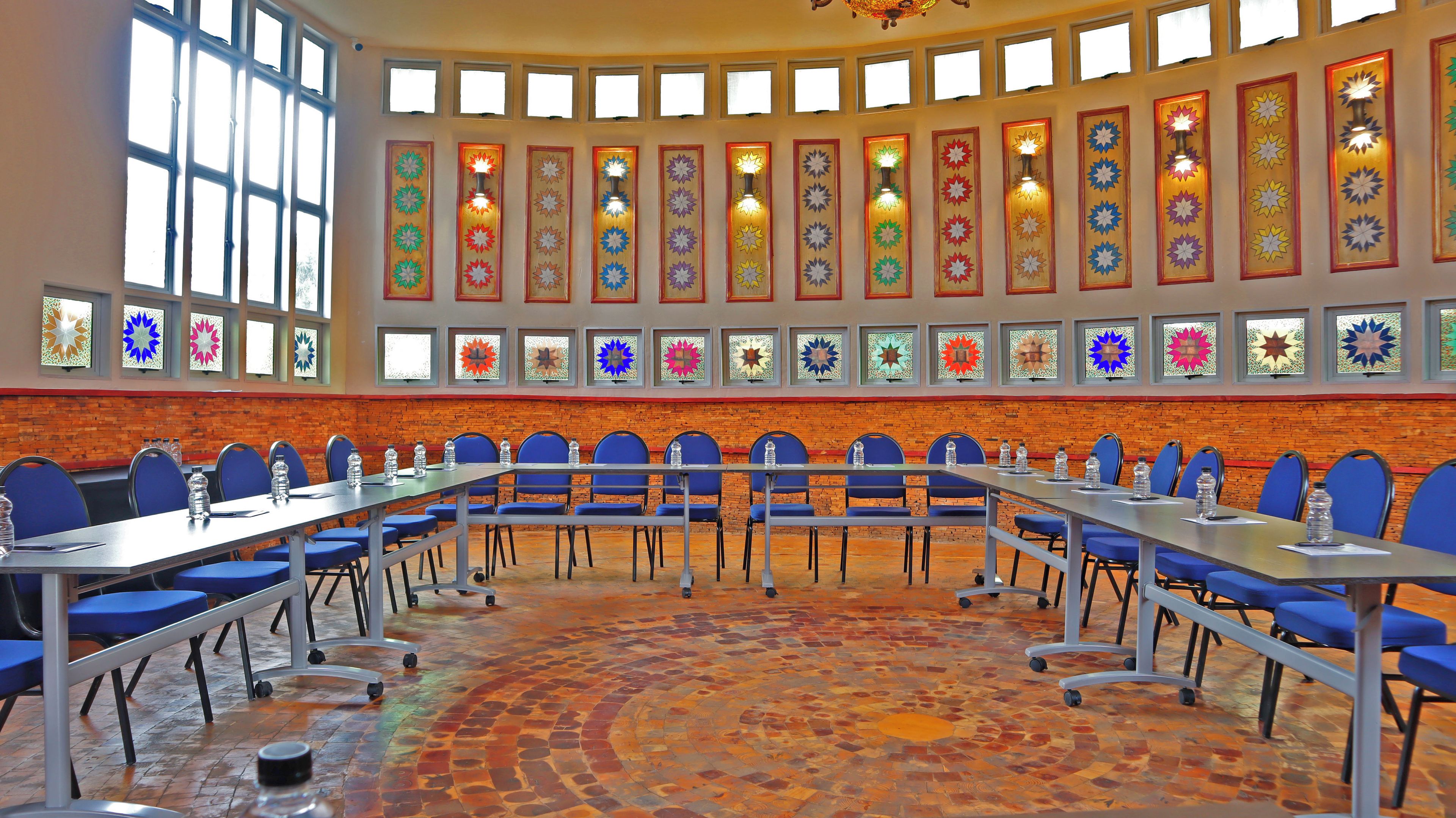 A conference room with a long table, blue chairs, and a patterned floor.
