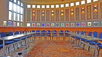 A conference room with a long table, blue chairs, and a patterned floor.