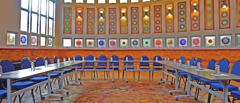 Un salón de conferencias con una mesa larga, sillas azules y un suelo estampado.