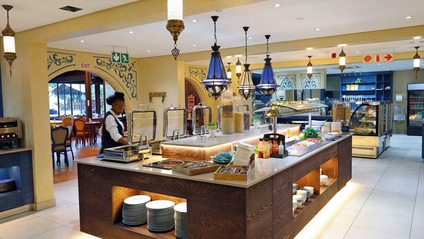 Un espace buffet proposant une variété de plats, un présentoir de buffet et un membre du personnel chargé de servir les clients.