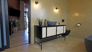 A modern bathroom with a black vanity, a sink, and a toilet. There are two wall-mounted lights and a potted plant on the vanity. - Qurtuba Resort And Events (Johannesburg)