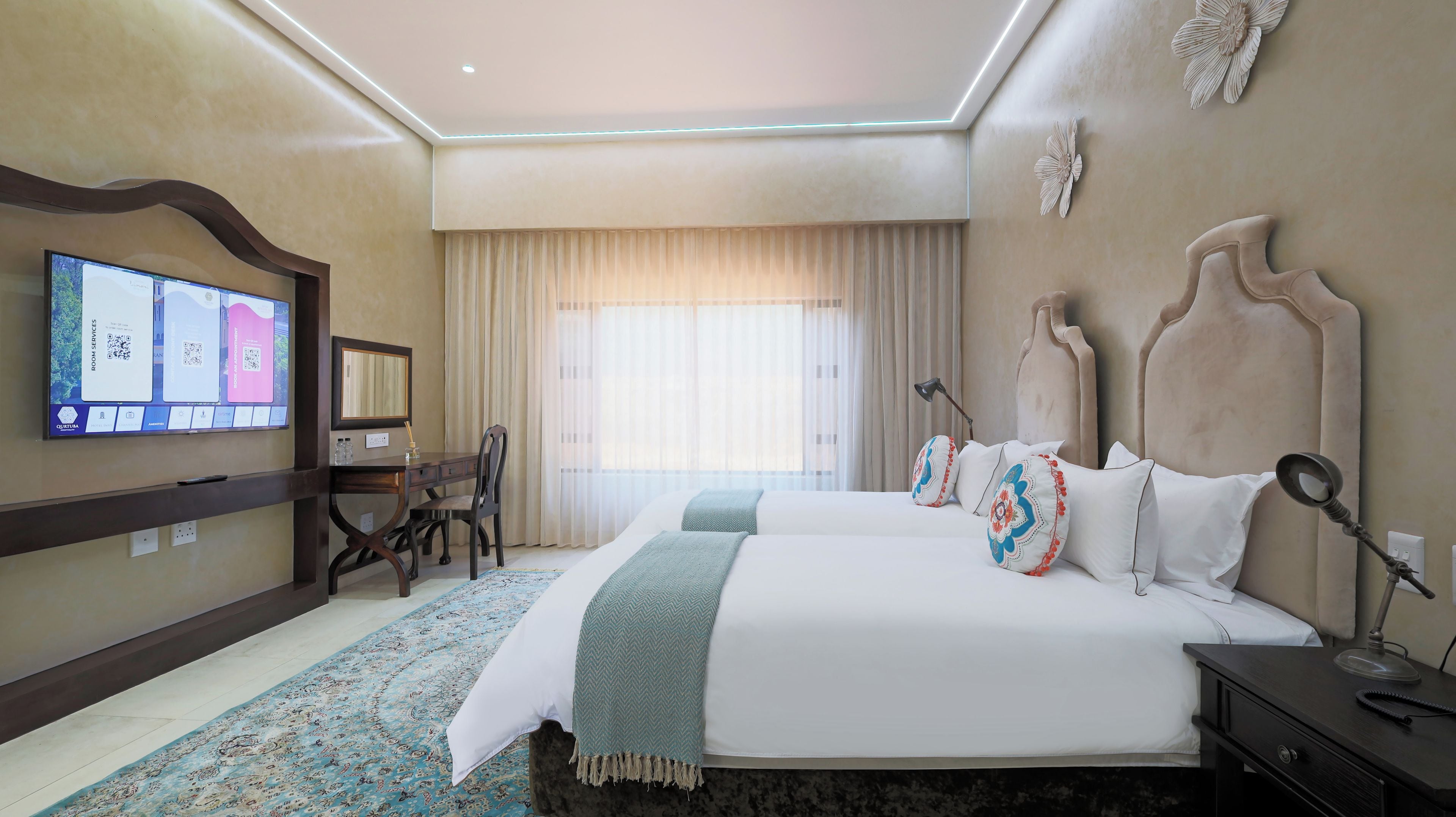 Habitación de hotel con una cama grande, un escritorio con silla, un televisor de pantalla plana en la pared y un elemento decorativo en la pared.