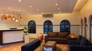A lobby with a reception desk, seating area, and arched windows. - Qurtuba Resort And Events (Johannesburg)