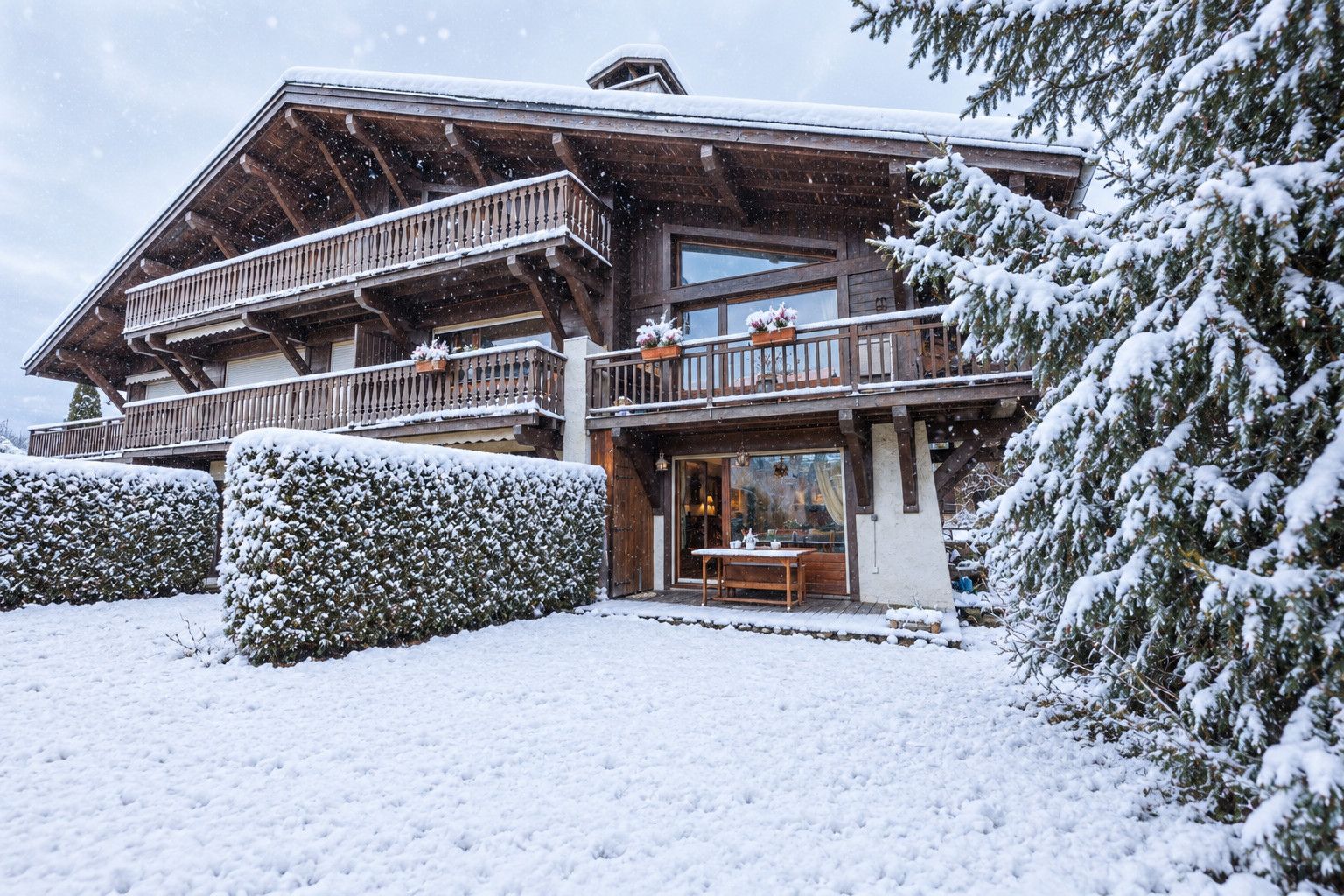 Een houten chalet met een balkon, een eethoek en een besneeuwde omgeving.