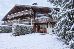 A wooden chalet with a balcony, a dining area, and snow-covered surroundings. - Appartement Piton - Welkeys (Megève)