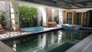 An indoor swimming pool with clear water, surrounded by lounge chairs and potted plants. - RedDoorz @ Occazia Hotel Pampanga (Bacolor)