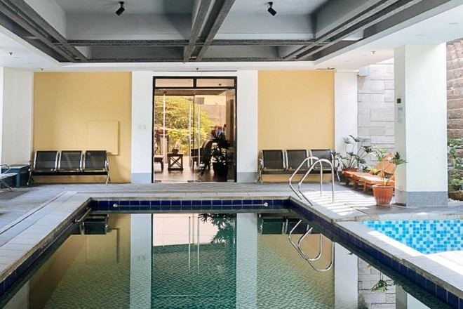 A swimming pool area with lounge chairs and a door leading to another room.