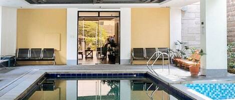 A swimming pool area with lounge chairs and a door leading to another room.
