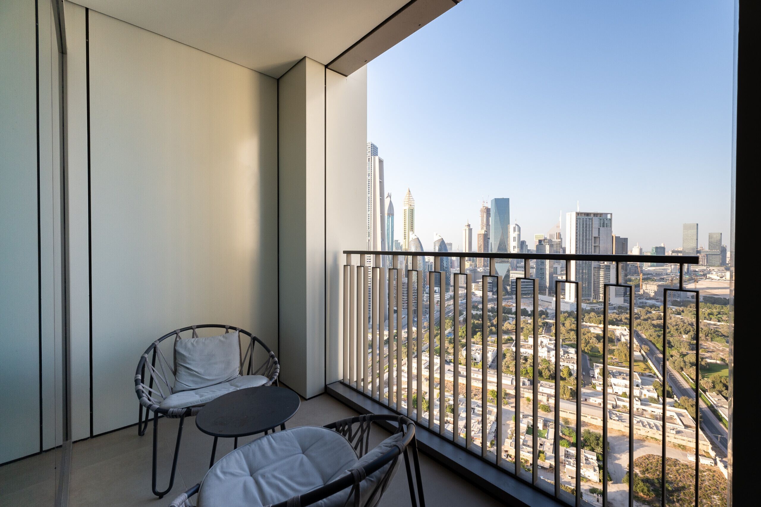 A balcony with a view of a cityscape, featuring modern buildings and a clear sky.