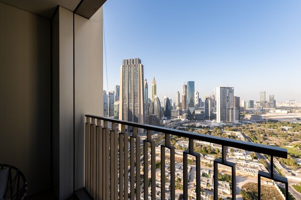 A balcony with a cityscape view, featuring modern high-rise buildings and a clear sky.
