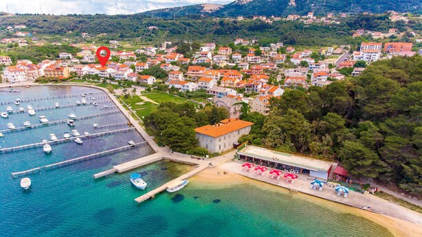 An aerial view of a coastal town with a marina, residential buildings, and a small commercial area with outdoor seating. - Amazing apartment in Palit with house sea view (Palit)