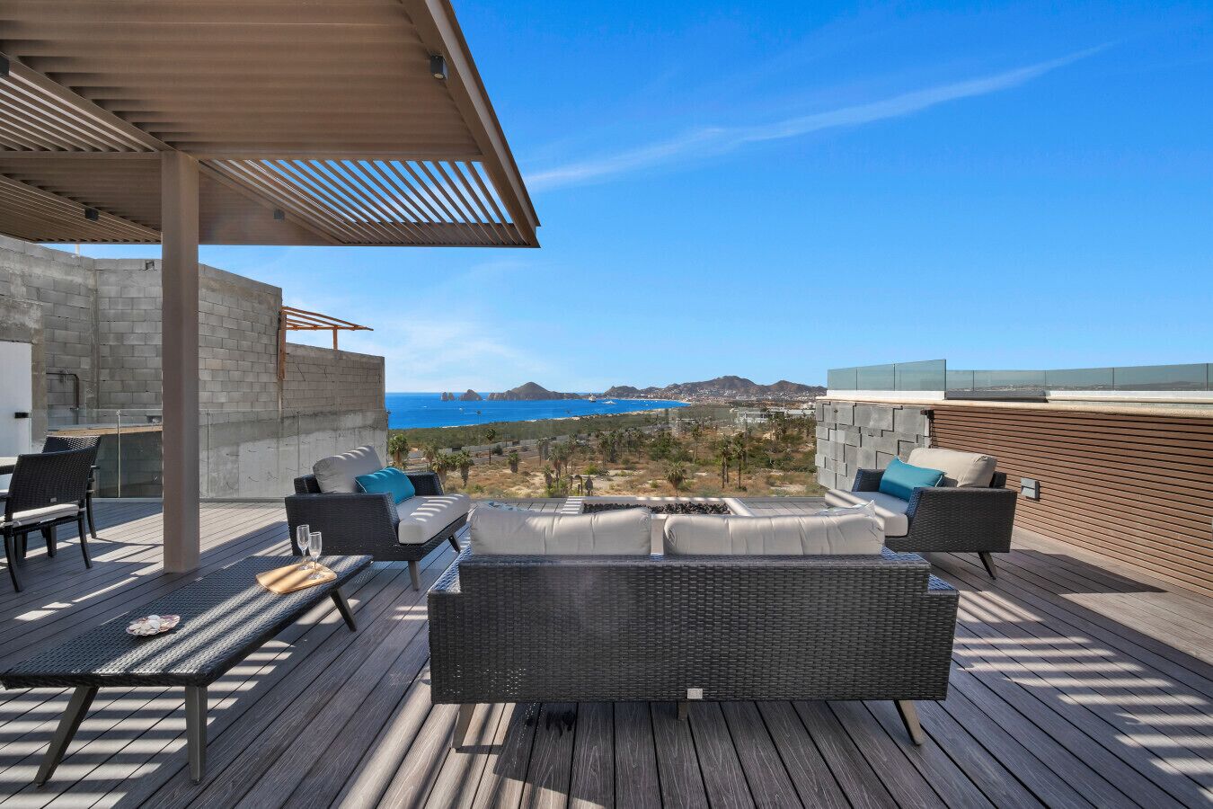 En takterrass med utemöbler, en pergola och utsikt över kusten.