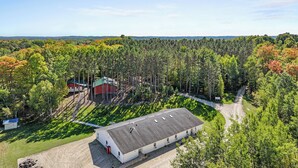 Suuri, tasakattoinen teollisuusrakennus, jonka ympärillä on tiheää metsää ja jonka yllä on kirkas taivas.