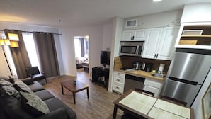 A compact living space with a sofa, coffee table, kitchenette, and a dining area.
