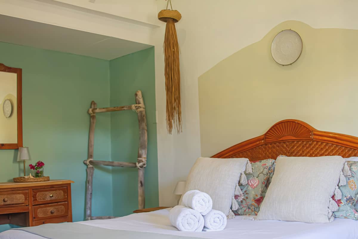 Un dormitorio con una cama de madera, una escalera de madera, un reloj de pared y un adorno colgante tejido.