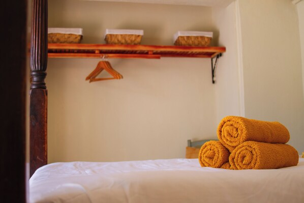 A neatly made bed with rolled towels and a wooden headboard. - Landhuis Francia (Willemstad)