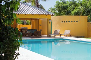 Una piscina al aire libre, sombrillas, sillones reclinables de piscina