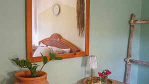 Una habitación con una cama de madera, una planta en maceta, una lámpara y un espejo en la pared.