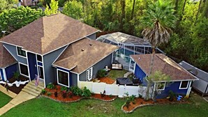 A two-story house with a covered patio and a swimming pool.