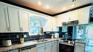 A modern kitchen with white cabinets, a stainless steel range, and a dishwasher.
