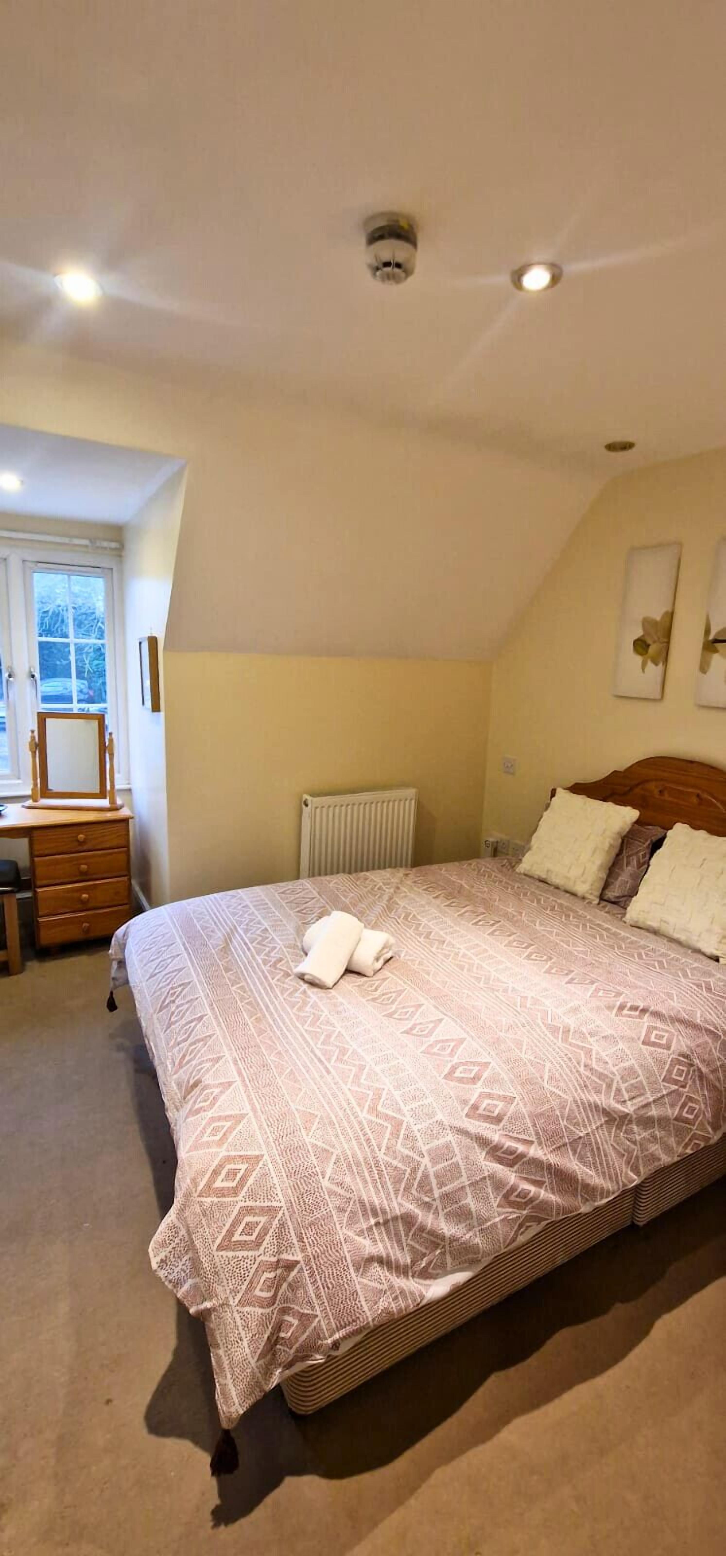 A bedroom with a bed, a dresser, a radiator, and a window.