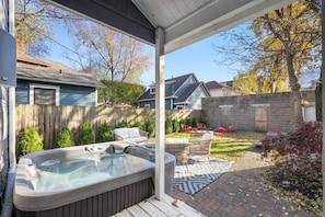 Ein Garten mit Whirlpool, Gartenmöbeln und einer Pflasterterrasse.