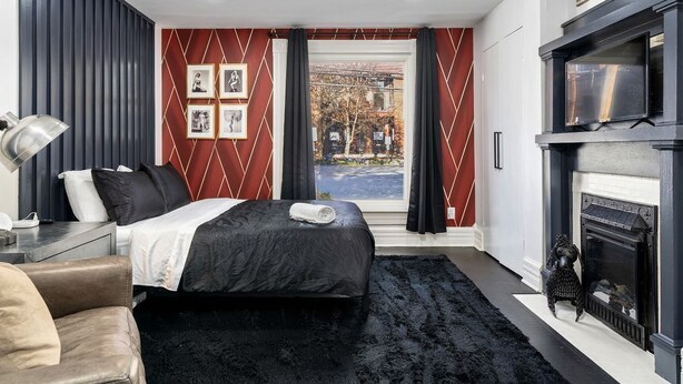 Une chambre moderne avec un lit, une cheminée et une vue sur la rue.