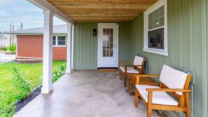 Eine Veranda mit Holzstühlen und einer Tür.