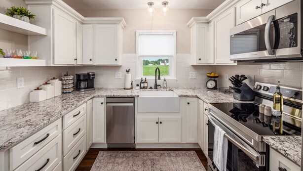 A modern kitchen with white cabinetry, a stainless steel dishwasher, a microwave, and an oven.