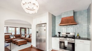 A modern kitchen with stainless steel appliances, a large window, and a cozy seating area with a brown leather sofa. - Whirlwind Waters Paradise (Russells Point)