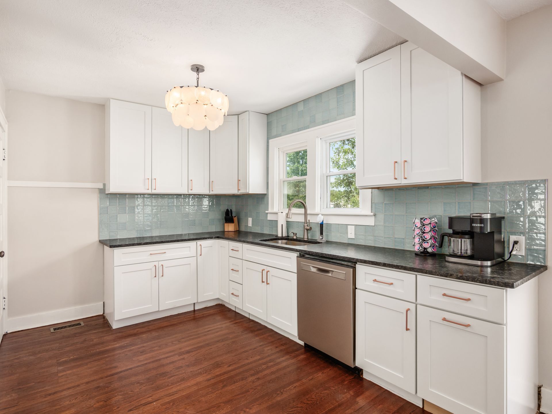 A modern kitchen with white cabinets, a black countertop, and a stainless steel dishwasher.