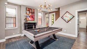 A pool table in a room with a fireplace, a chandelier, and artwork on the walls. - The Pop Fusion Pad in Short North (Columbus)