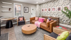 A modern living room with a brown sofa, a round wooden coffee table, and a grey carpet. - The Pop Fusion Pad in Short North (Columbus)