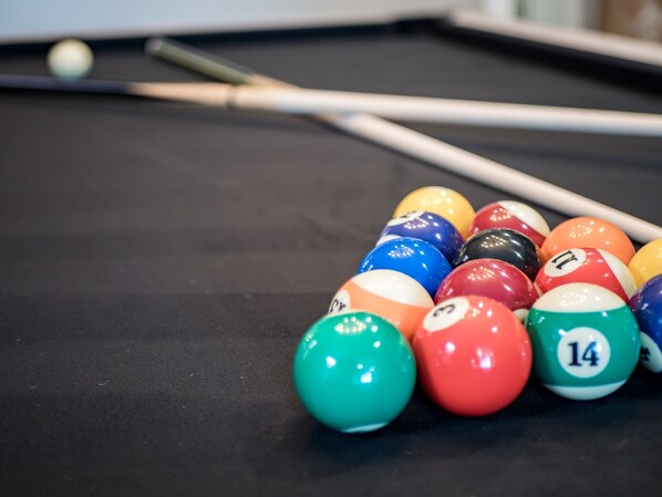 A pool table with colorful billiard balls and a pool cue.